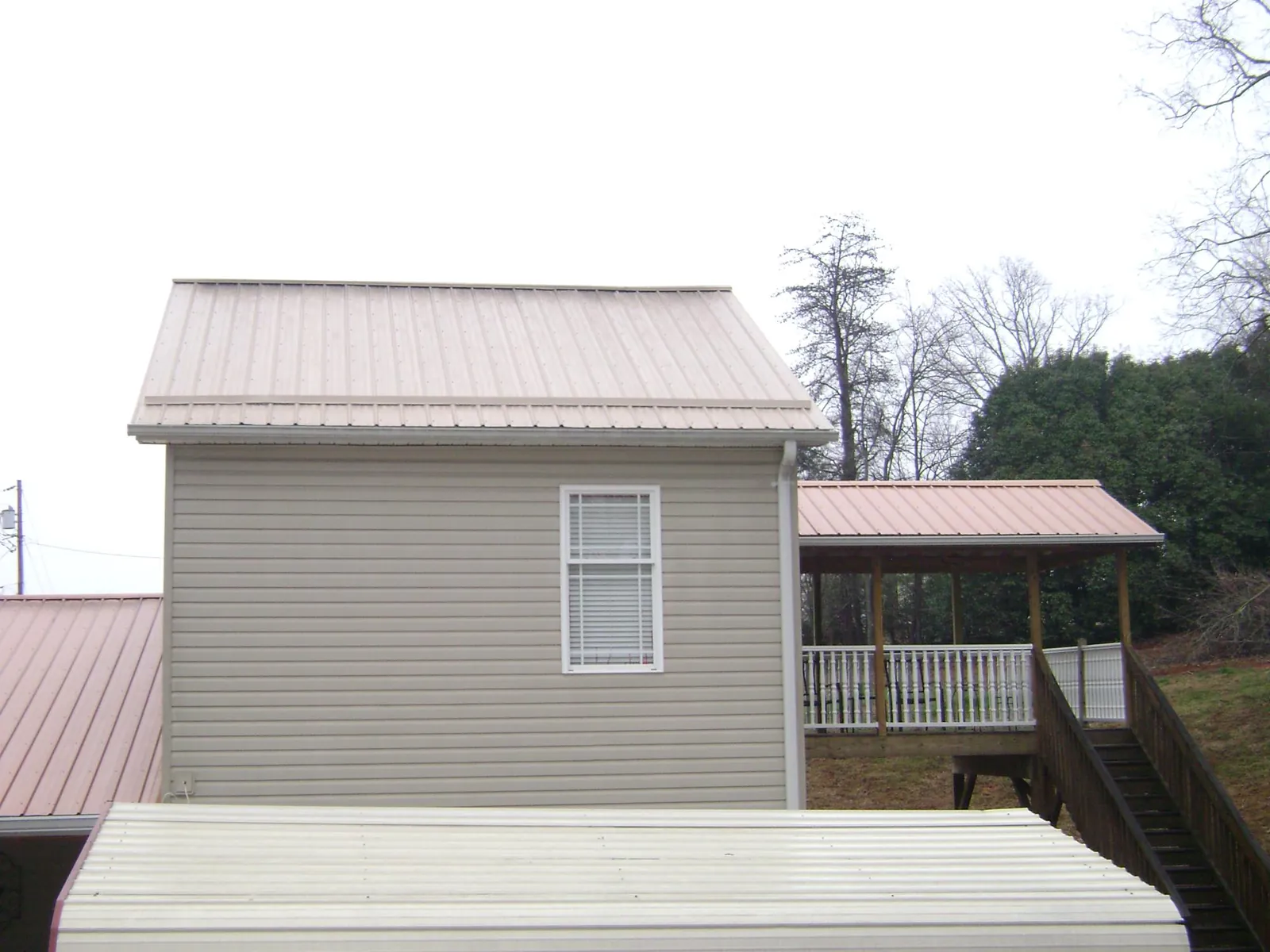 Tan metal roofs on a two story addition and attached porch, from a Roof Replacement job in Akron